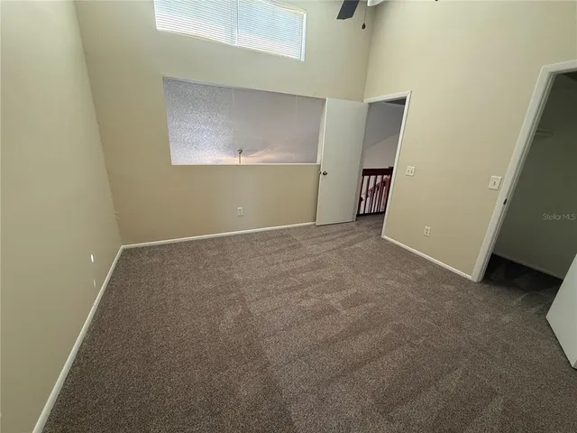 an empty room that has a window and a fan