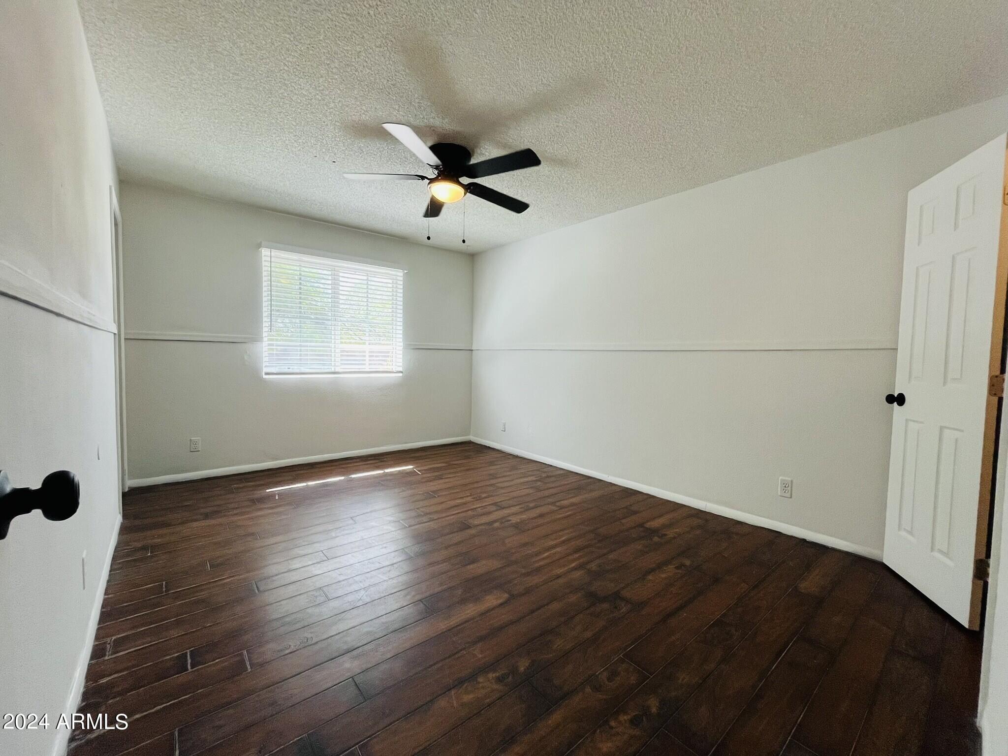 5154 West Berkeley Road Phoenix, AZ 85035 - Photo 12 of 19 an empty room with wooden floor fan and windows