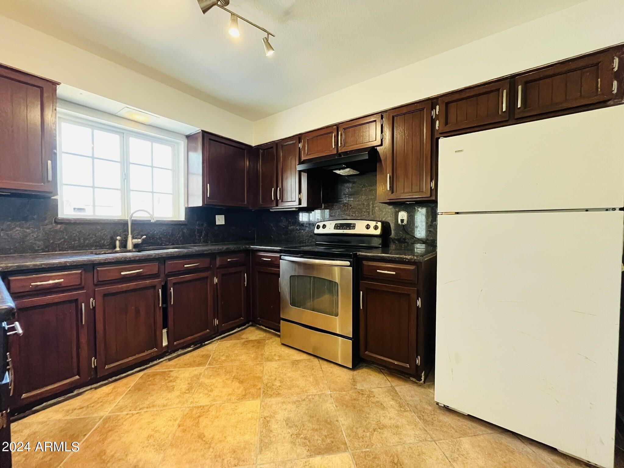 5154 West Berkeley Road Phoenix, AZ 85035 - Photo 4 of 19 a kitchen with a refrigerator sink and cabinets