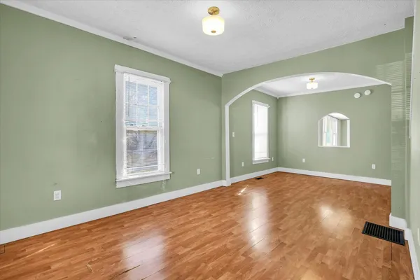 a view of an empty room with wooden floor and a window