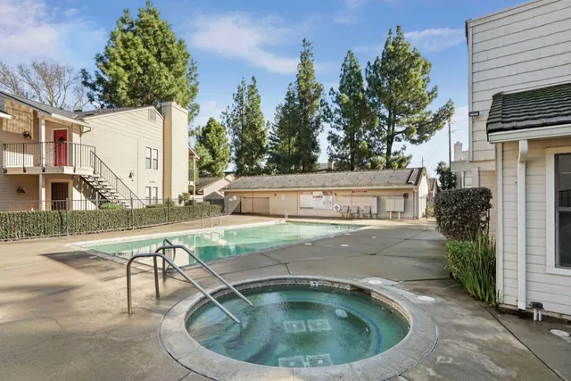 a view of a white house with a big yard and potted plants