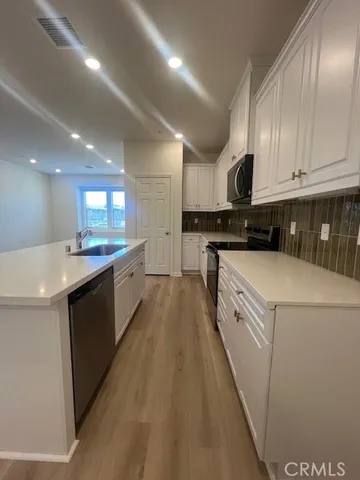 a kitchen with granite countertop a sink a counter space stainless steel appliances and cabinets