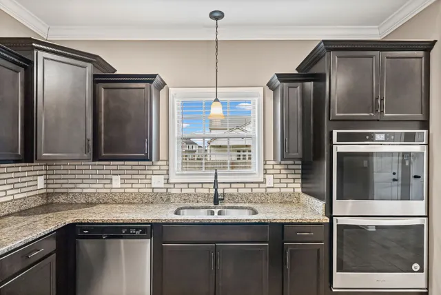 a kitchen with granite countertop a sink and stainless steel appliances
