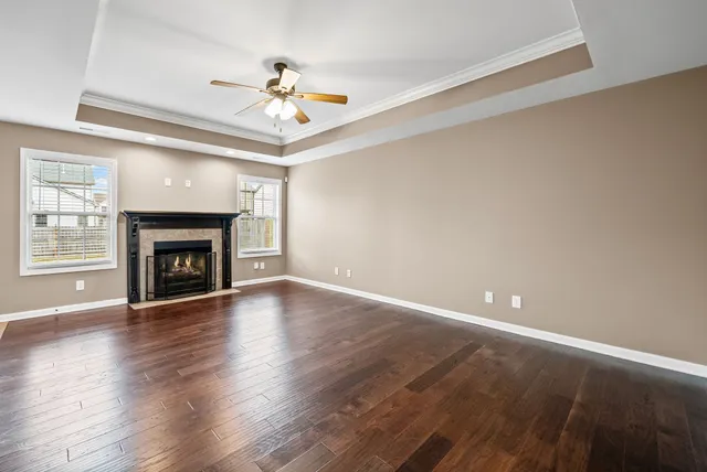 a view of an empty room with wooden floor fireplace and a window
