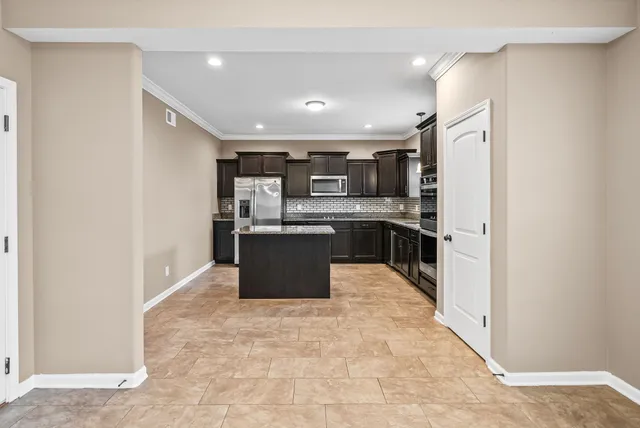 a kitchen with stainless steel appliances kitchen island granite countertop a refrigerator and a sink