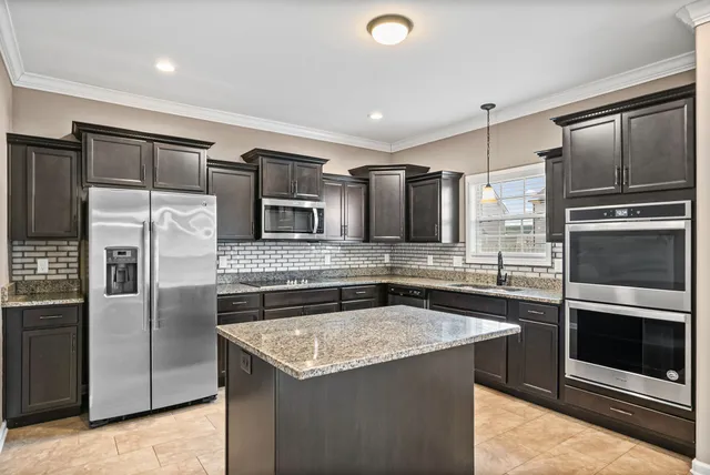 a kitchen with stainless steel appliances granite countertop a refrigerator a stove and a sink