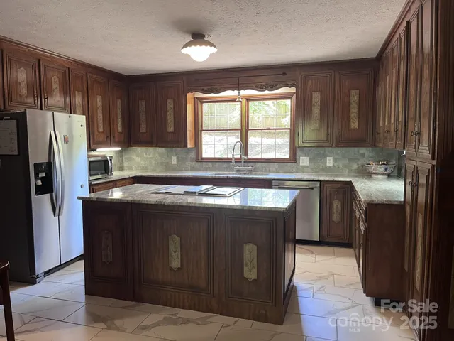 a kitchen with stainless steel appliances granite countertop a stove a refrigerator and a sink