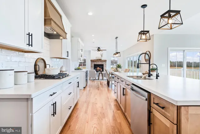 a kitchen with stainless steel appliances granite countertop a sink a stove a refrigerator and island with wooden floor