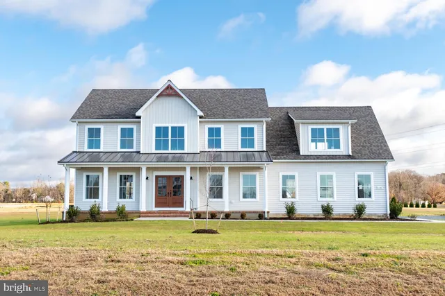a front view of a house with a garden and trees