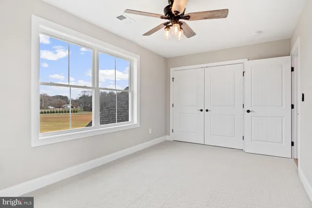 an empty room with a chandelier fan and windows