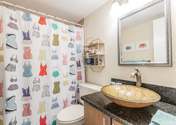 a bathroom with a granite countertop toilet sink and mirror