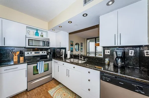 a kitchen with stainless steel appliances granite countertop a stove a sink and a microwave