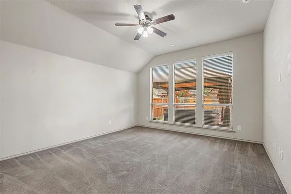 an empty room with chandelier fan and windows