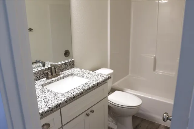 a bathroom with a granite countertop sink a toilet and shower