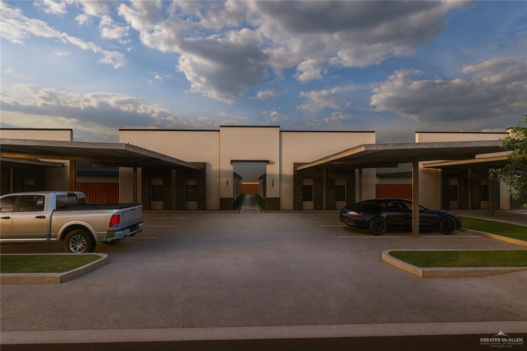 View of building exterior featuring covered and uncovered parking