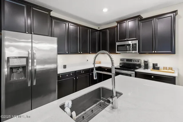a kitchen with granite countertop a refrigerator stove top oven and cabinets