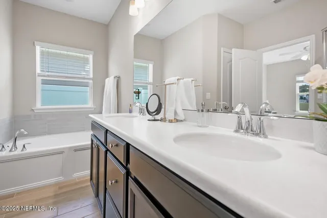 a bathroom with a sink double vanity granite tub shower and a mirror