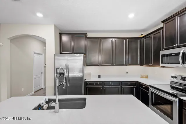 a kitchen with stainless steel appliances kitchen island granite countertop a refrigerator and a stove top oven