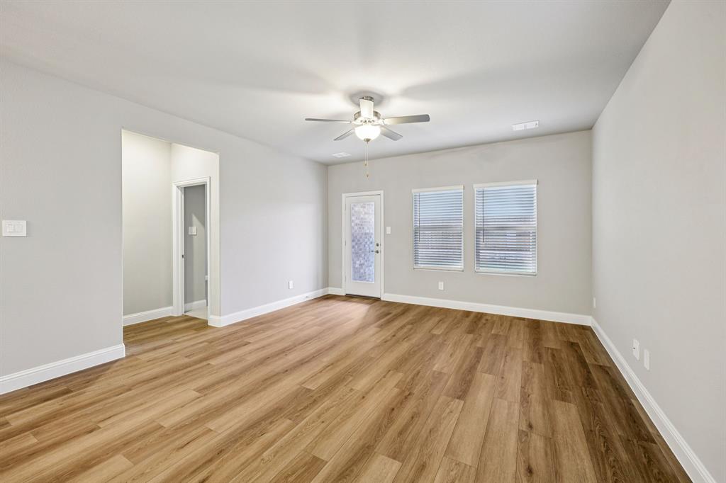 1721 Arches Road Anna, TX 75409 - Photo 8 of 39 an empty room with wooden floor ceiling fan and windows