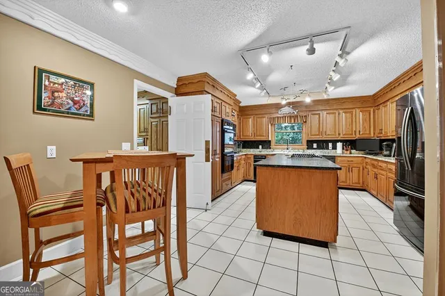 a large kitchen with stainless steel appliances granite countertop a sink and a refrigerator