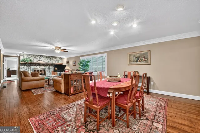 a kitchen with stainless steel appliances kitchen island granite countertop a refrigerator a stove a sink a dining table and chairs with wooden floor