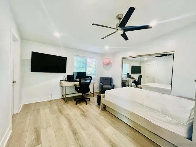a bedroom with a bed a couch and a flat screen tv