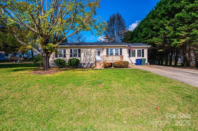 a view of a house with a big yard and large trees