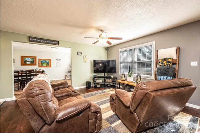 a living room with furniture kitchen view and a wooden floor