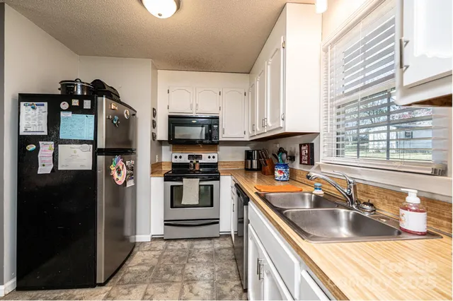 a kitchen with stainless steel appliances granite countertop a stove top oven a sink a dining table and chairs