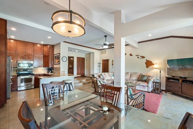 a living room with lots of furniture kitchen view and a large window