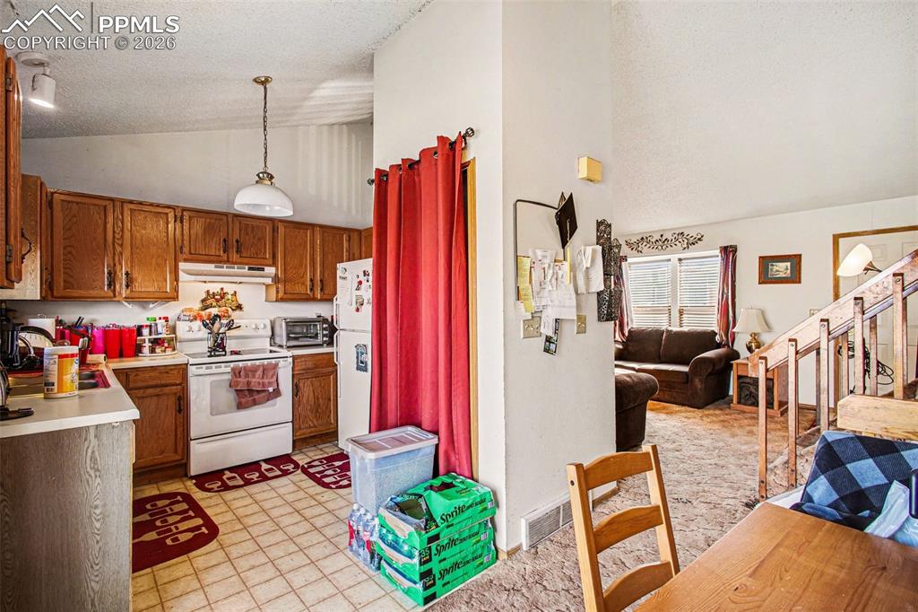 921 Candlestar Loop North Fountain, CO 80817 - Photo 9 of 23 a kitchen with stainless steel appliances kitchen island granite countertop a refrigerator a stove top oven a sink dishwasher and a dining table with chairs