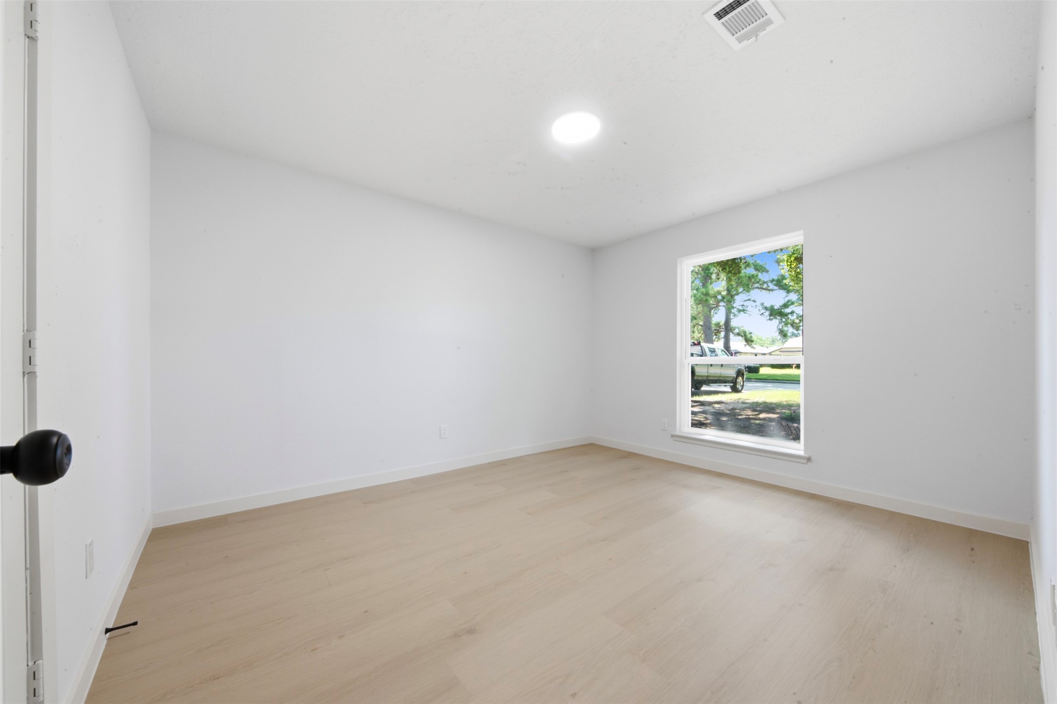 9518 Landry Boulevard Spring, TX 77379 - Photo 20 of 38 Bright and airy room with fresh white walls, light wood flooring, and a large window offering picturesque views of the outdoors.