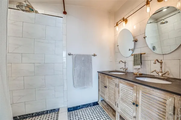 a bathroom with a granite countertop sink a mirror and shower