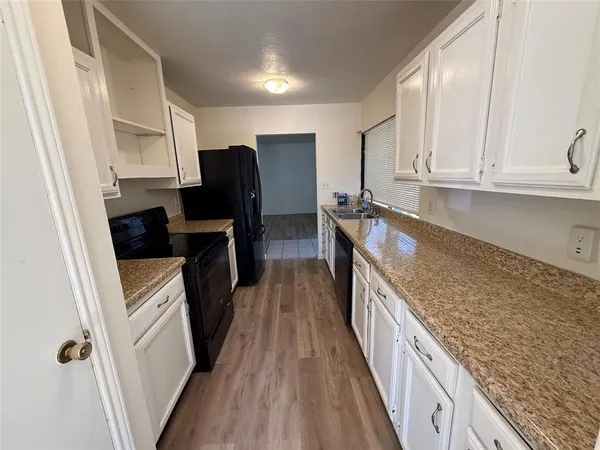 a kitchen with granite countertop a refrigerator stove and sink