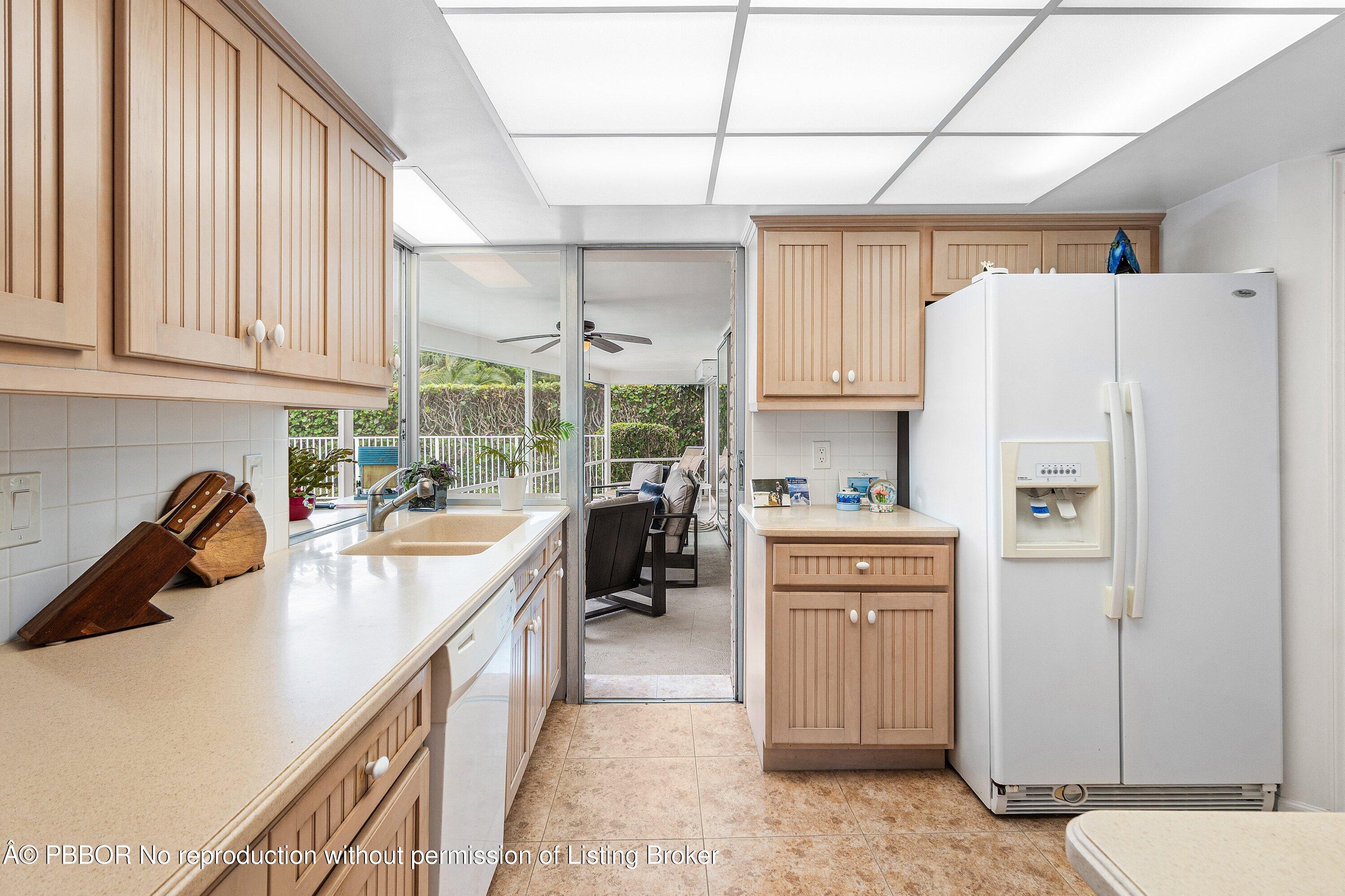 23 Sabal Island Drive Ocean Ridge, FL 33435 - Photo 10 of 16 a kitchen with granite countertop a refrigerator a sink dishwasher a stove and white cabinets with wooden floor