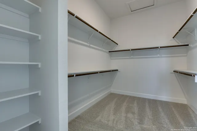 an empty room with a chandelier fan and closet area
