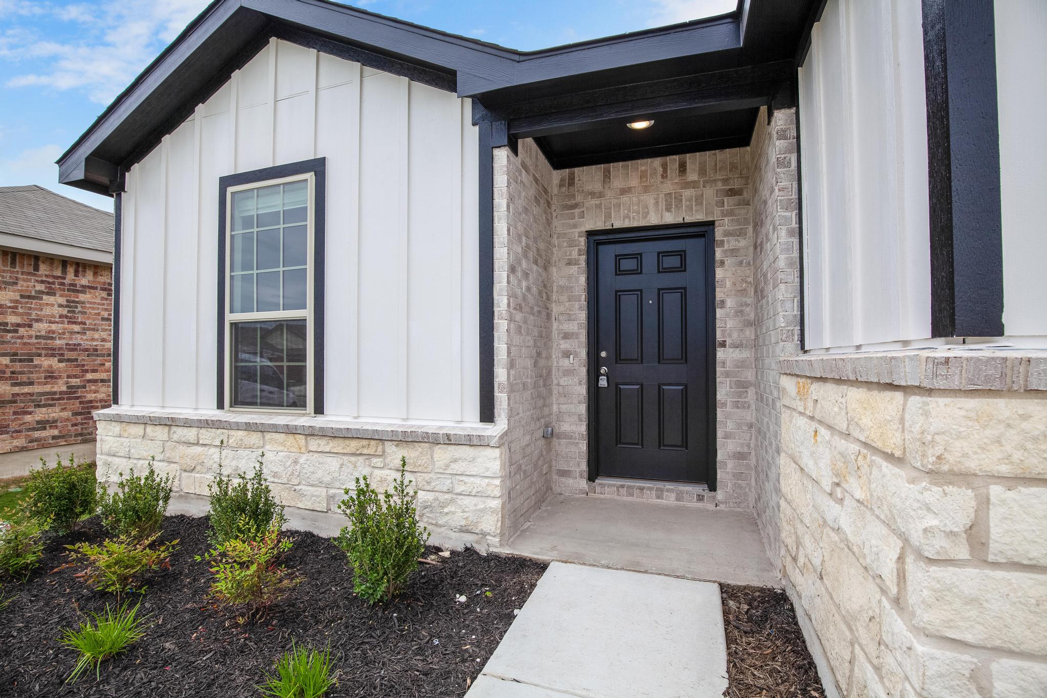 200 Janice Road Taylor, TX 76574 - Photo 2 of 25 A welcoming entry featuring a black paneled door and mixed material facade for appealing curb appeal.