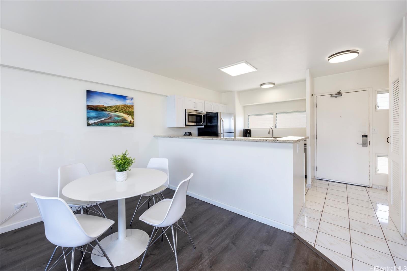 2161 Kalia Road, Unit 1012 Honolulu, HI 96815 - Photo 15 of 25 a kitchen with stainless steel appliances kitchen island granite countertop a refrigerator a stove a microwave oven a dining table and chairs with wooden floor