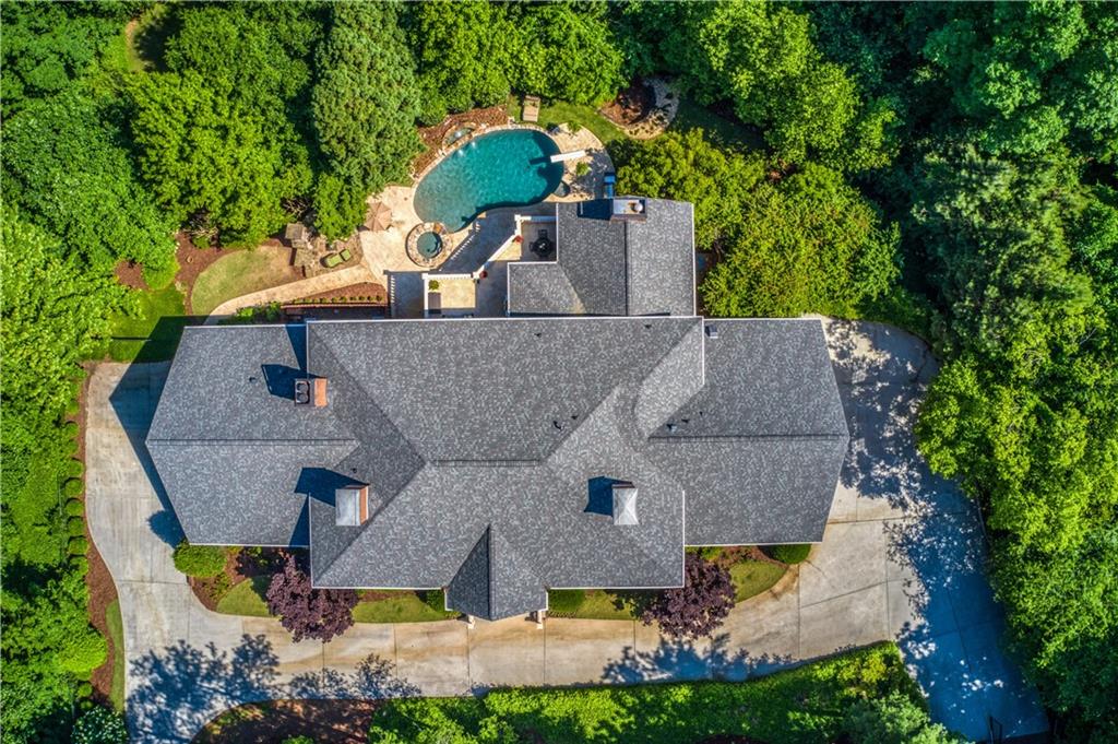 an aerial view of a house with swimming pool and large trees