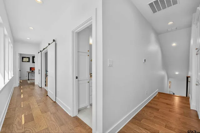 a view of a hallway with wooden floor and staircase
