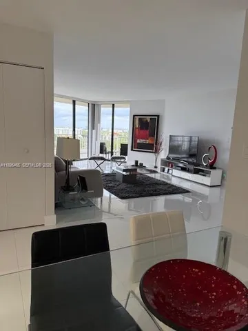 a living room with furniture floor to ceiling window and a flat screen tv