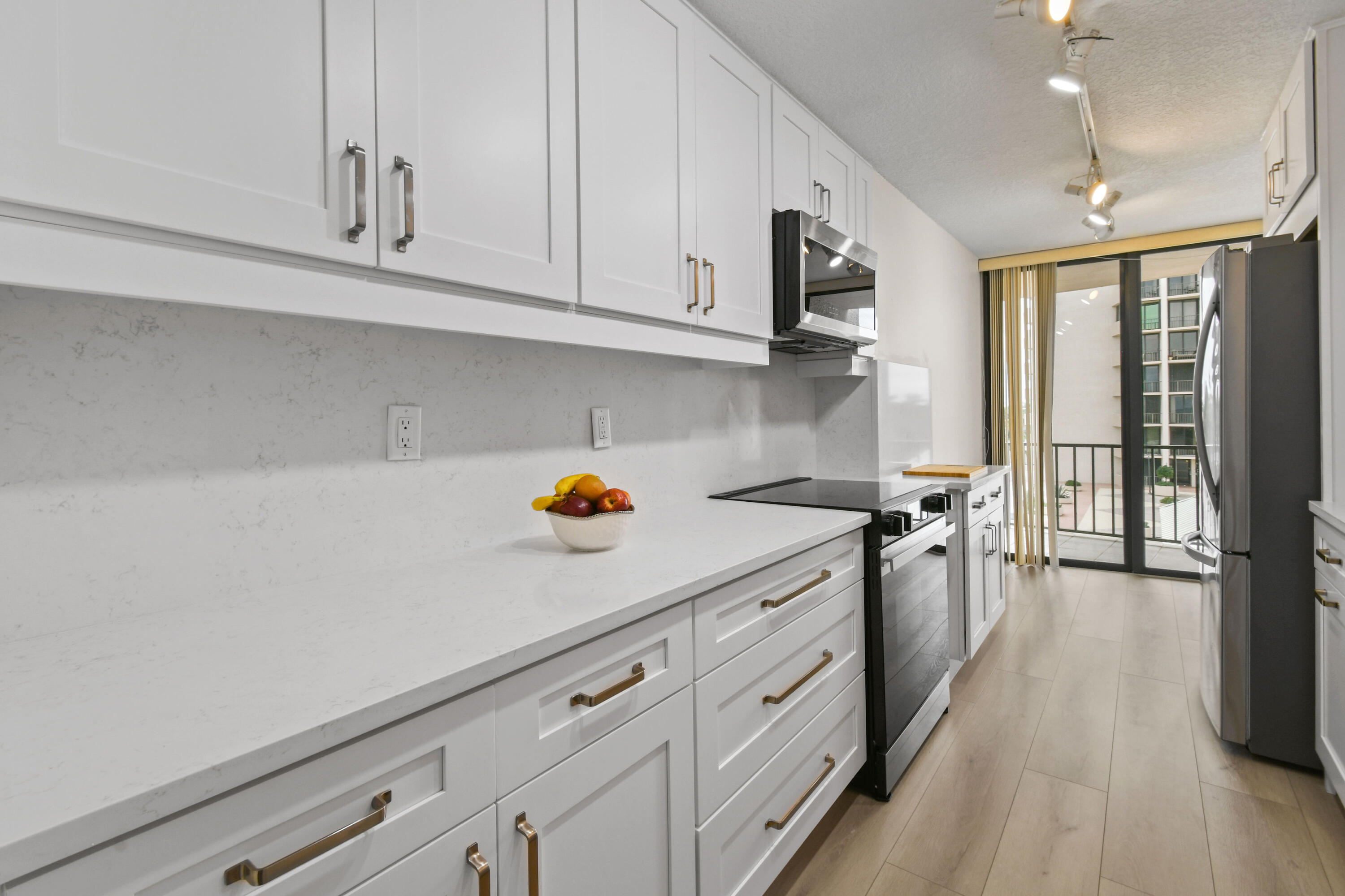 4200 North Ocean Drive, Unit 1 Riviera Beach, FL 33404 - Photo 31 of 59 a kitchen with stainless steel appliances white cabinets and wooden floor