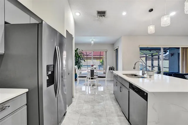 a kitchen with stainless steel appliances kitchen island granite countertop a refrigerator and a sink