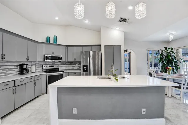 a kitchen with kitchen island granite countertop a sink cabinets and stainless steel appliances