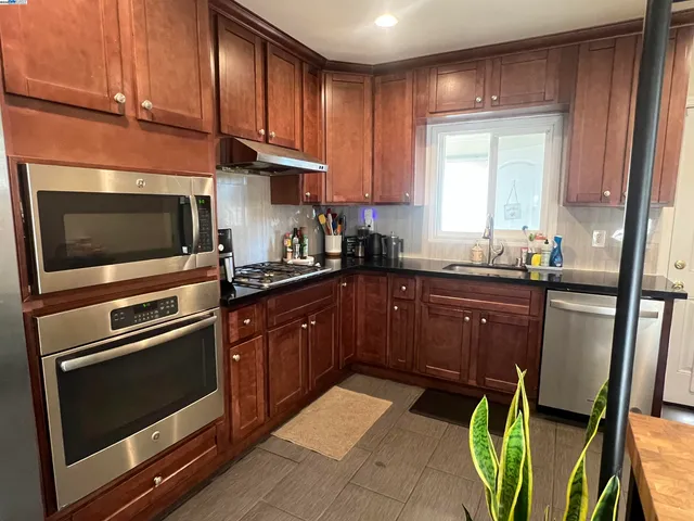a kitchen with granite countertop wooden cabinets stainless steel appliances and a window