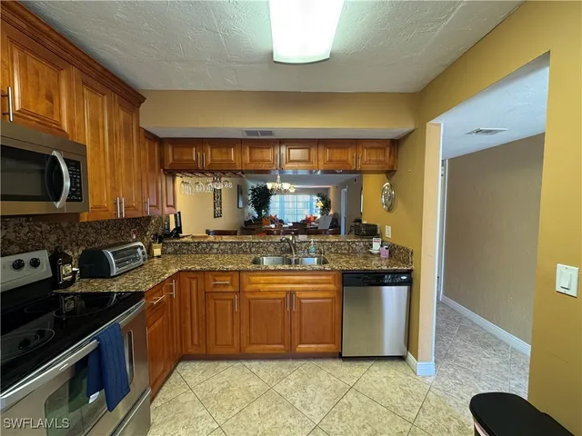 a kitchen with stainless steel appliances granite countertop a stove a sink and a microwave