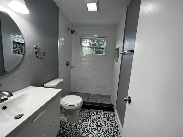 a bathroom with a sink a toilet a mirror and shower