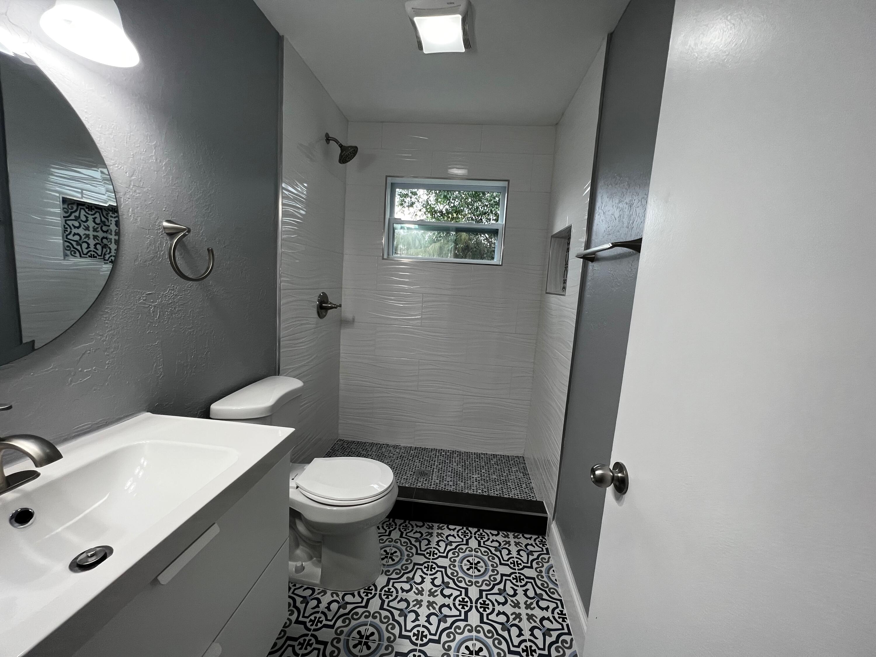 1147 Goldenrod Road Wellington, FL 33414 - Photo 6 of 18 a bathroom with a sink a toilet a mirror and shower