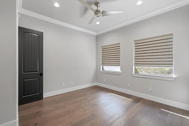 an empty room with wooden floor ceiling fan and windows