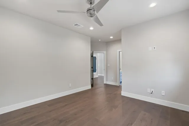 an empty room with wooden floor and a ceiling fan